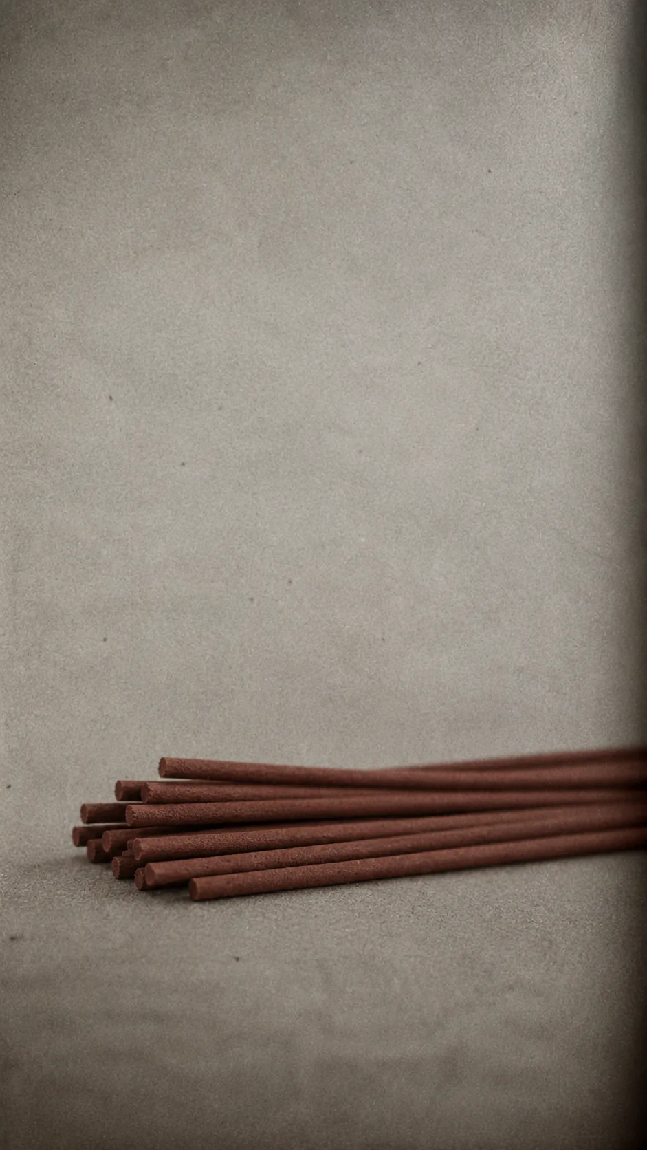 A small stack of unlit Japanese incense on a grey stone surface