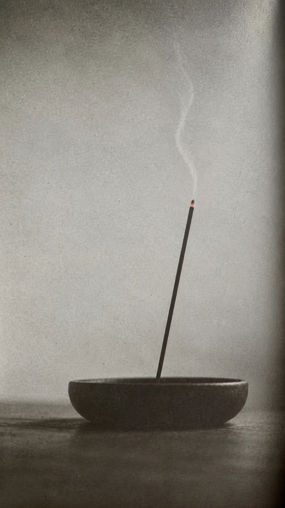 Incense burning in a shallow stone bowl, a thread of smoke rising