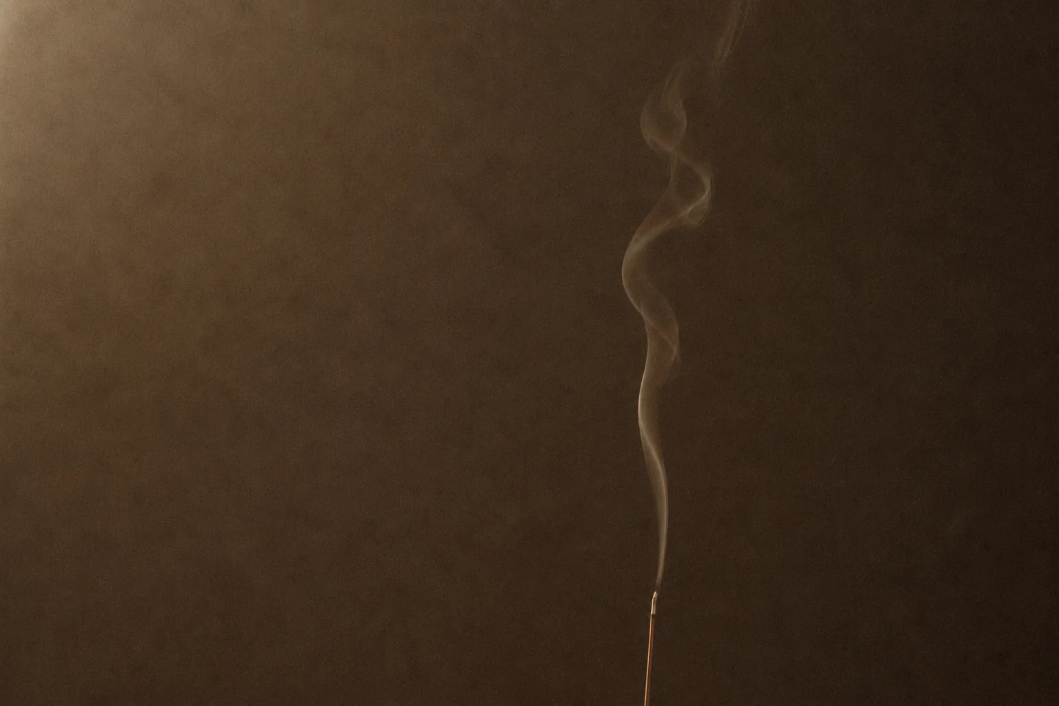 A single thread of smoke rising in a dim room